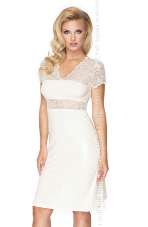 A woman with long blonde hair is wearing the Irall Cameron Nightdress in cream by Irall, which features delicate lace detailing on the sleeves and upper bodice. The knee-length nightdress has a fitted waist and is made from super soft fabric that flows gracefully. She is posing against a plain white background.