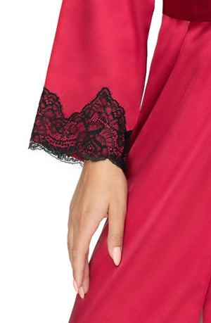 Close-up of a person's hand wearing the Irall Juniper Burgundy Dressing Gown by Irall, featuring black lace trim on the sleeve. The hand is relaxed and resting against the side, showcasing the intricate lace design and the smooth, luxurious fabric. The nails are manicured and painted light pink.