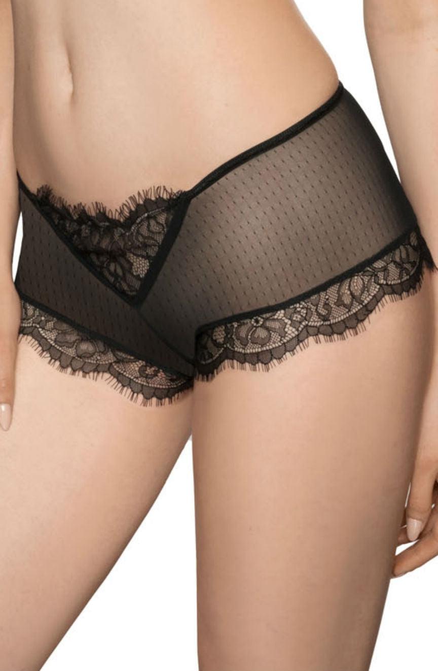 A person wearing the Roza Idrisa Black Brief from the Roza brand, featuring black, sheer mesh fabric with lace detailing along the waistband and leg openings. The fabric is see-through with a delicate polka dot pattern, and the lace trim showcases an exquisite floral design reminiscent of eyelash lace. The image focuses on the lower torso and thighs.