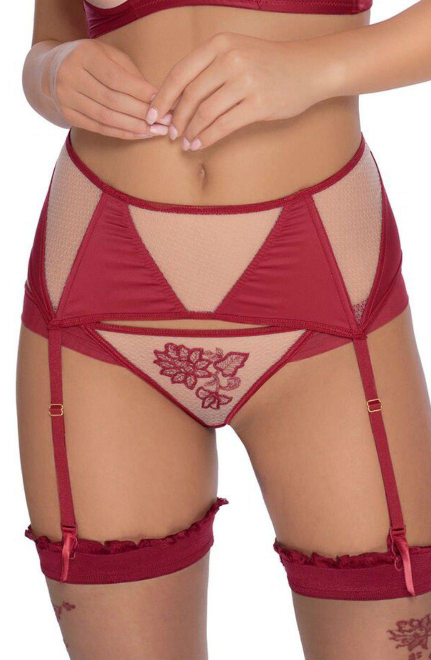 Close-up of a woman's lower torso wearing the Roza Mehendi Thong Claret by Roza, featuring sheer mesh panels adorned with embroidered henna flowers. The set includes a garter belt attached to matching red garter straps holding up thigh-high stockings with ruffled tops. Her hands are touching one another.